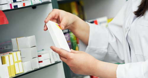 A pharmacist taking a packet of medication off a shelf
